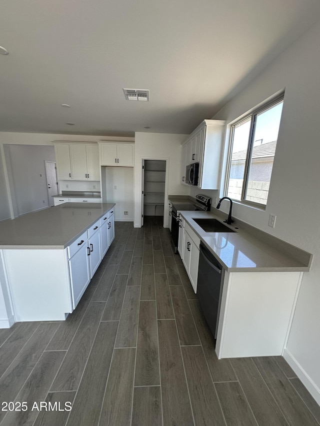 kitchen featuring a sink, stainless steel appliances, wood finish floors, and visible vents