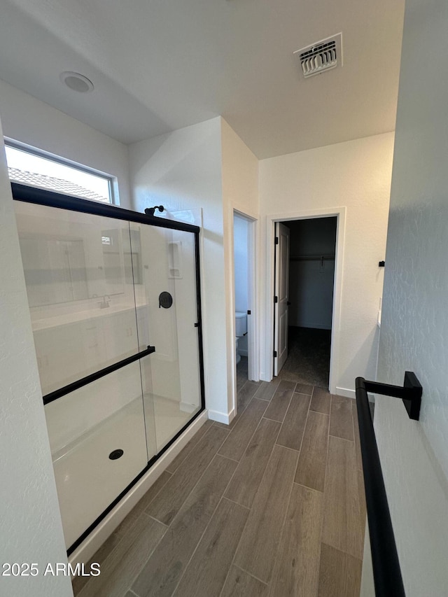 full bath with visible vents, toilet, a shower stall, baseboards, and wood tiled floor