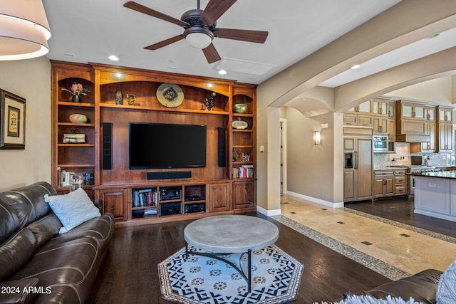 living room featuring a ceiling fan, built in features, baseboards, recessed lighting, and arched walkways