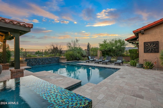 pool at dusk featuring a fenced in pool, a fenced backyard, and a patio area