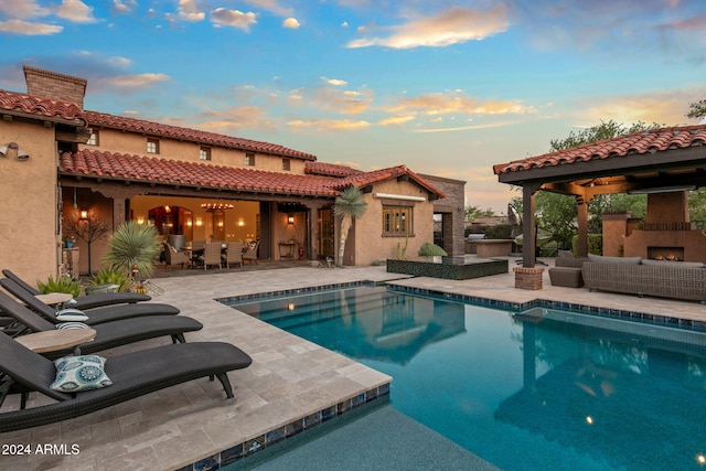 outdoor pool featuring an outdoor living space with a fireplace, a patio, outdoor dining area, and exterior kitchen