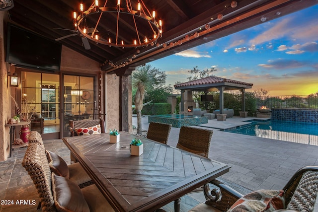 patio terrace at dusk featuring a gazebo, outdoor dining area, an outdoor pool, and fence
