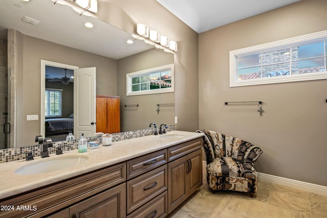 full bathroom with double vanity, baseboards, a sink, and ensuite bathroom