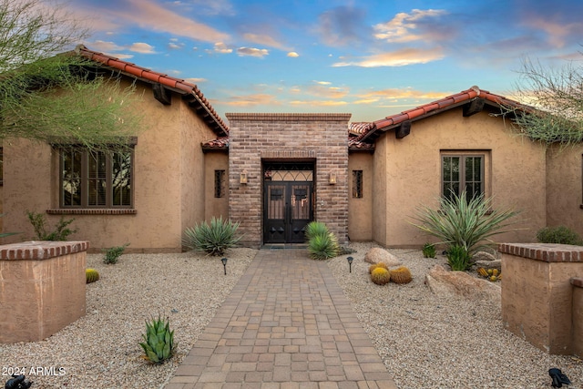 view of front of home featuring french doors, a tile roof, and stucco siding
