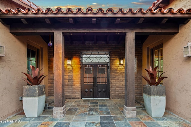 view of exterior entry featuring a porch, stucco siding, and french doors