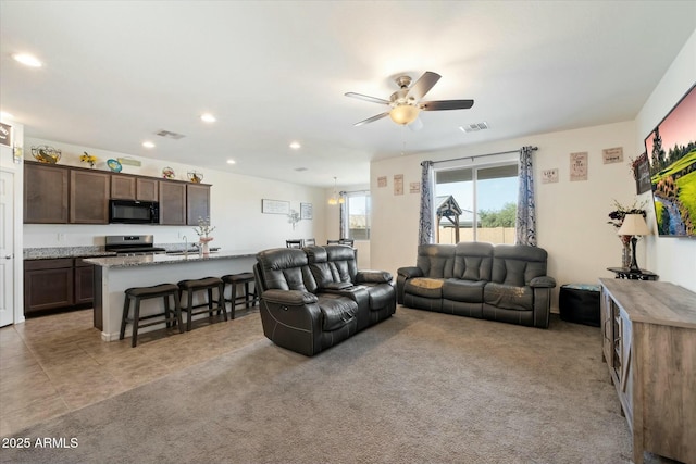 living room with sink, light colored carpet, and ceiling fan