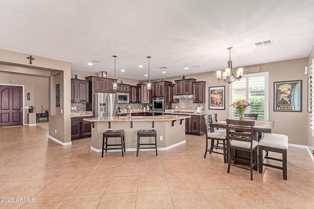 19427 W Colter St, Litchfield Park, AZ 85340 - kitchen with stainless steel appliances, backsplash, dark brown cabinetry, a chandelier, and a spacious island