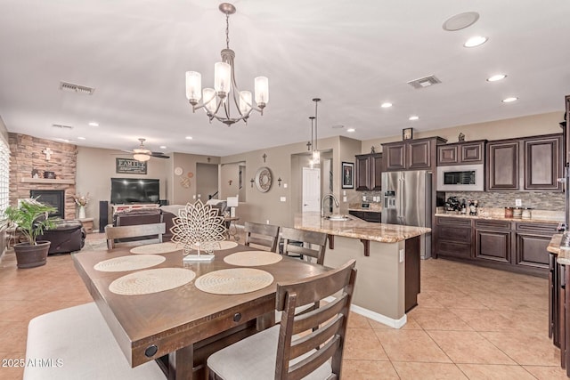 19427 W Colter St, Litchfield Park, AZ 85340 - dining room featuring light tile patterned floors, ceiling fan, a chandelier, recessed lighting, and a fireplace