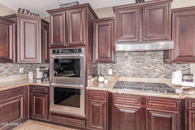19427 W Colter St, Litchfield Park, AZ 85340 - kitchen featuring appliances with stainless steel finishes, backsplash, light stone counters, and under cabinet range hood