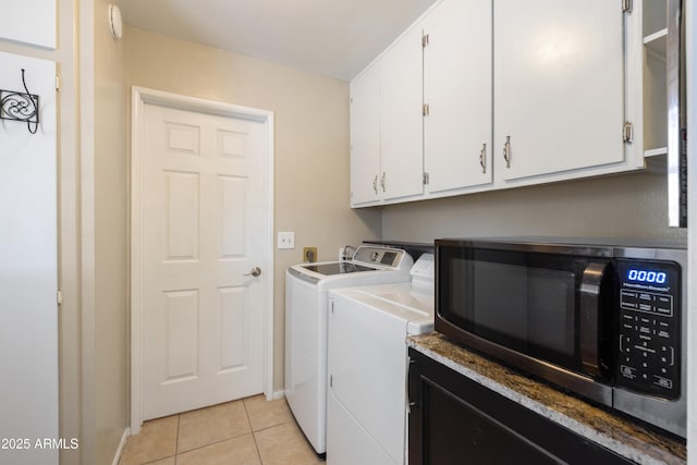 clothes washing area featuring light tile patterned floors, cabinets, and washer and dryer