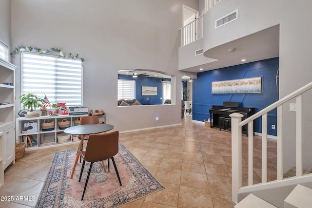 2210 W Goldmine Mountain Dr, Queen Creek, AZ 85144 - tiled dining room with visible vents, baseboards, a ceiling fan, and a towering ceiling
