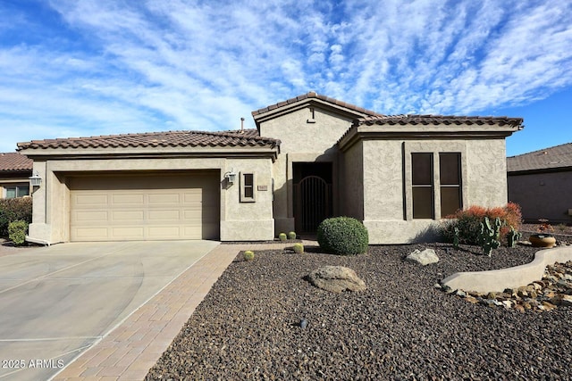 view of front of home featuring a garage, concrete driveway, a tiled roof, a gate, and stucco siding