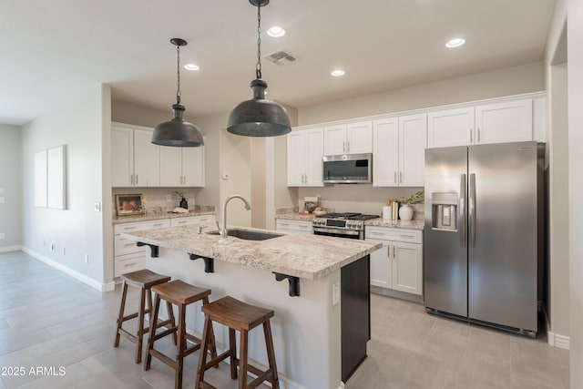 2680 E Daniel Dr, Gilbert, AZ 85298 - kitchen with appliances with stainless steel finishes, white cabinets, a kitchen island with sink, a breakfast bar area, and recessed lighting