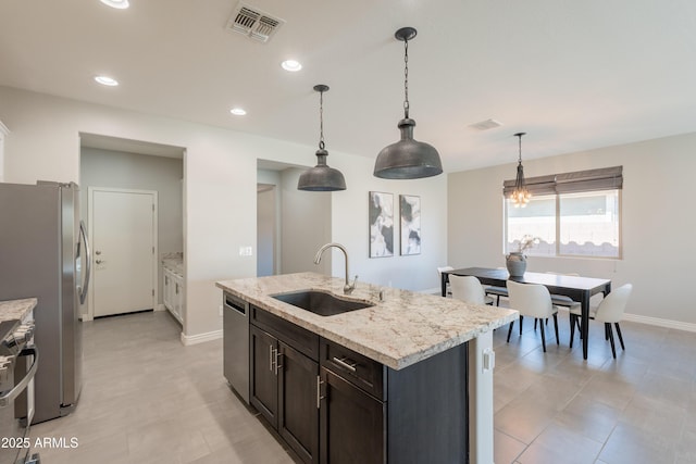 2680 E Daniel Dr, Gilbert, AZ 85298 - kitchen with appliances with stainless steel finishes, a chandelier, decorative light fixtures, a kitchen island with sink, and light stone countertops