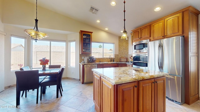 kitchen featuring vaulted ceiling, decorative backsplash, light stone countertops, decorative light fixtures, and stainless steel appliances