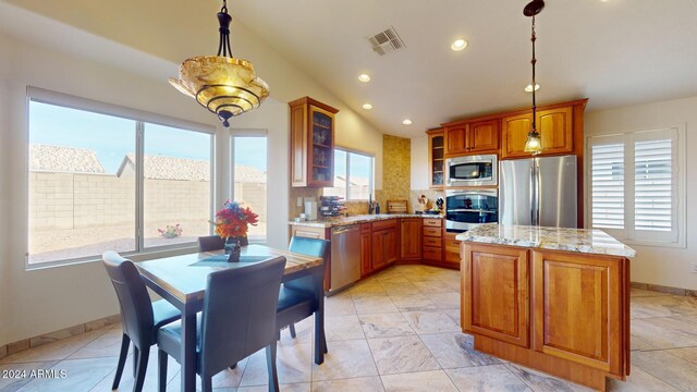 kitchen with a center island, lofted ceiling, backsplash, appliances with stainless steel finishes, and decorative light fixtures