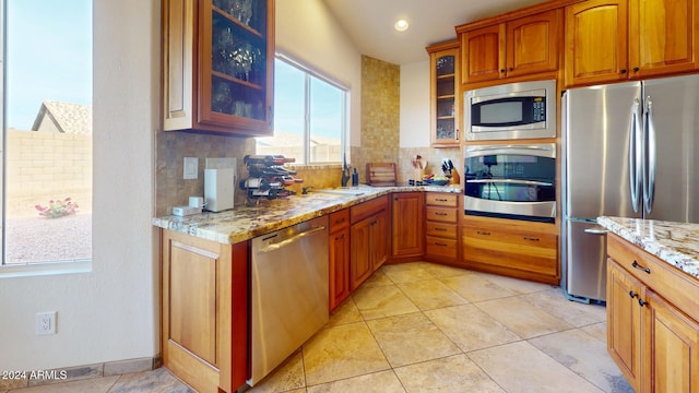 kitchen featuring light stone counters, light tile patterned floors, appliances with stainless steel finishes, and tasteful backsplash