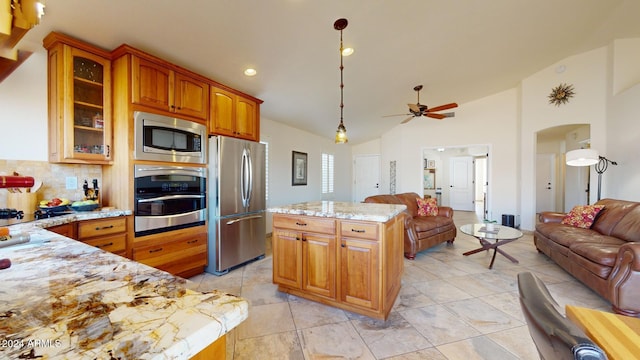 kitchen with hanging light fixtures, light stone counters, backsplash, lofted ceiling, and appliances with stainless steel finishes