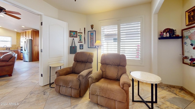 living area featuring ceiling fan, light tile patterned floors, and sink