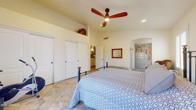 bedroom featuring vaulted ceiling, ceiling fan, ensuite bathroom, and two closets