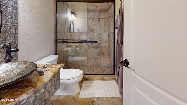 bathroom with tile patterned flooring, toilet, and a shower with door