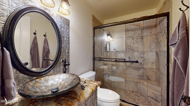 bathroom with toilet, an enclosed shower, and sink