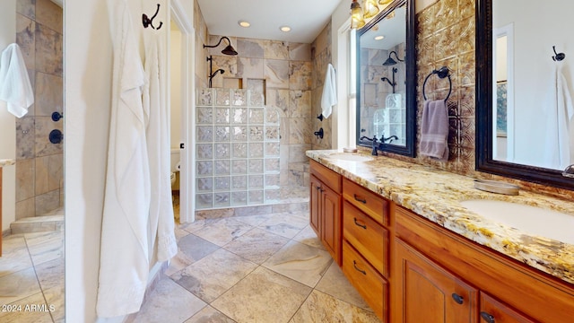 bathroom featuring a tile shower, vanity, and toilet