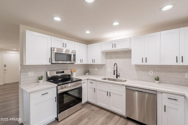 3620 E Ludlow Dr, Phoenix, AZ 85032 - kitchen with appliances with stainless steel finishes, a sink, white cabinetry, light stone countertops, and light wood-type flooring