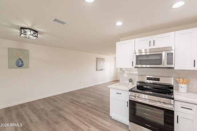 3620 E Ludlow Dr, Phoenix, AZ 85032 - kitchen with appliances with stainless steel finishes, white cabinets, backsplash, light wood-type flooring, and recessed lighting