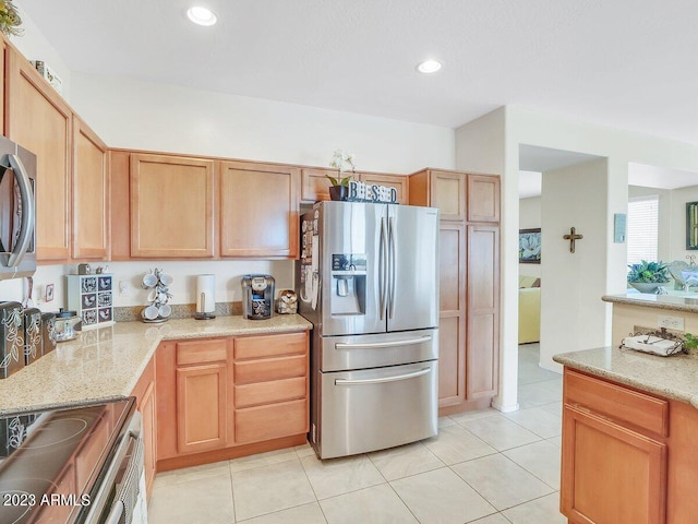 kitchen with appliances with stainless steel finishes, light stone counters, and light tile patterned floors