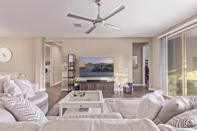 living room featuring washer / dryer, ceiling fan, and dark wood-type flooring