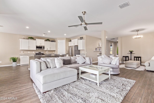 living room featuring ceiling fan with notable chandelier and wood-type flooring