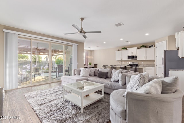 living room with ceiling fan and light wood-type flooring