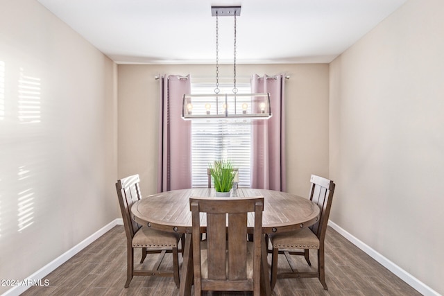 dining area featuring dark wood-type flooring and a notable chandelier