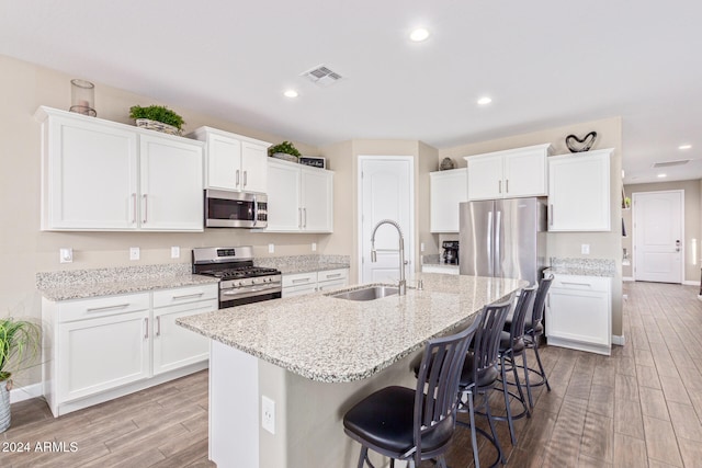 kitchen featuring appliances with stainless steel finishes, light hardwood / wood-style flooring, white cabinetry, and sink