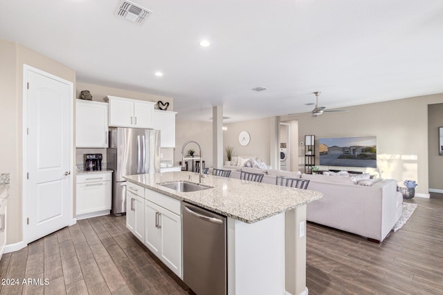 kitchen with dark wood-type flooring, stainless steel appliances, and a center island with sink