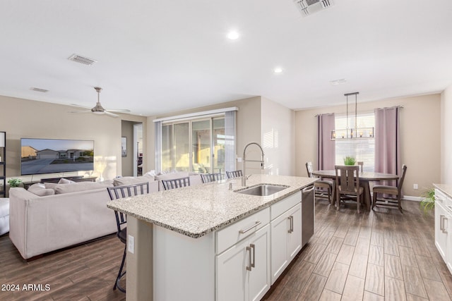 kitchen featuring sink, dark hardwood / wood-style floors, pendant lighting, a center island with sink, and white cabinets