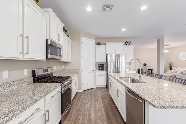 kitchen featuring white cabinets, sink, an island with sink, dark hardwood / wood-style flooring, and stainless steel appliances