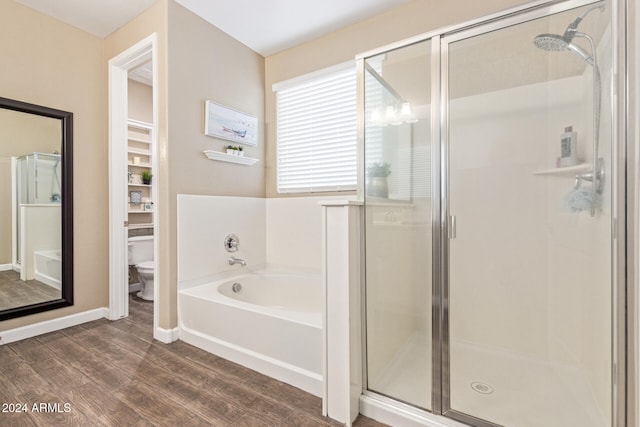 bathroom with hardwood / wood-style floors, toilet, and shower with separate bathtub