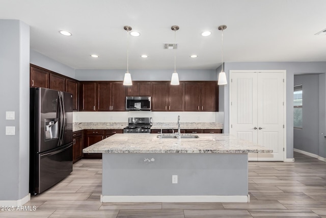 kitchen featuring dark brown cabinets, light stone countertops, stainless steel appliances, and a sink