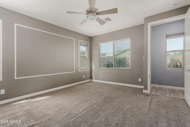 carpeted empty room with baseboards, visible vents, and ceiling fan