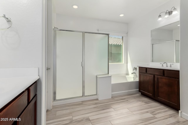 bathroom with vanity, a garden tub, and a stall shower