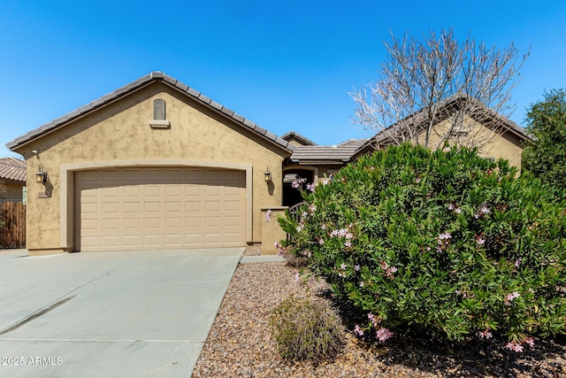 view of front of home featuring a tile roof, concrete driveway, a garage, and stucco siding