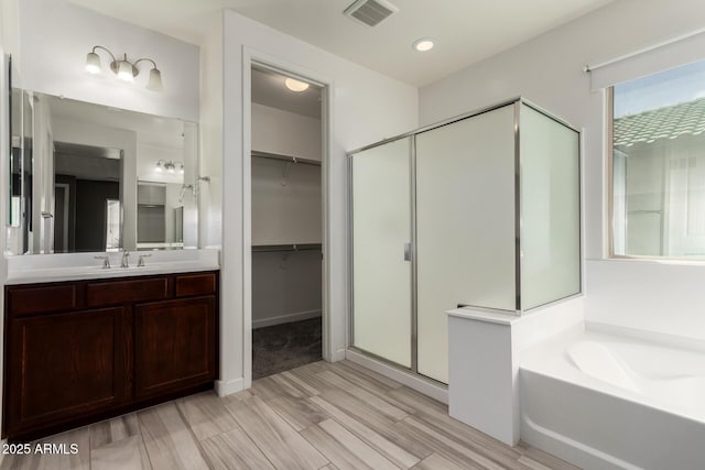 full bath featuring vanity, visible vents, a shower stall, a spacious closet, and a bath