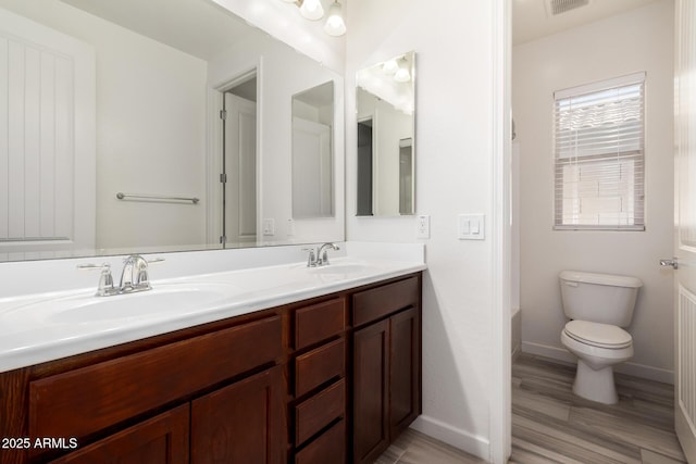 full bath featuring double vanity, toilet, baseboards, and a sink