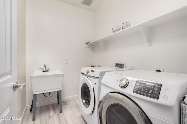 clothes washing area featuring visible vents, baseboards, laundry area, light wood-style floors, and separate washer and dryer