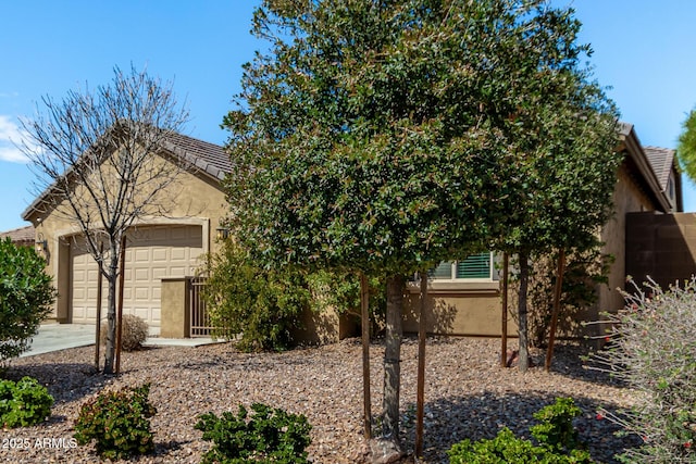 obstructed view of property featuring concrete driveway, a garage, and stucco siding