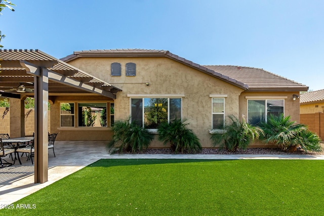 rear view of house featuring fence, a pergola, stucco siding, a patio area, and a lawn