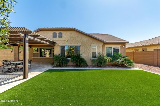 rear view of house with stucco siding, a lawn, a pergola, a patio, and fence