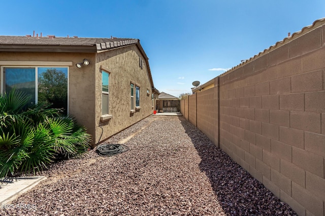 view of side of home with a fenced backyard and stucco siding